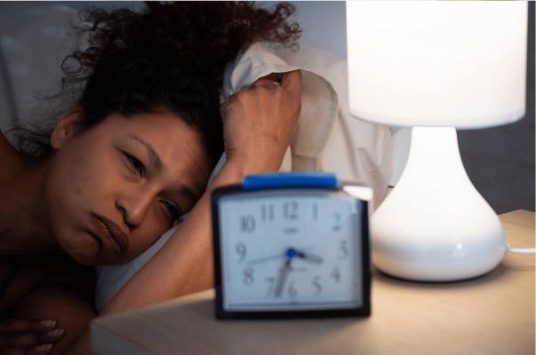 Tired woman looking at her alarm clock